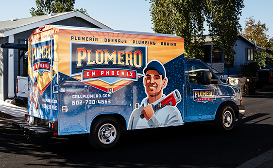 Camioneta de Plomero en Phoenix HVAC conduciendo por un vecindario residencial.